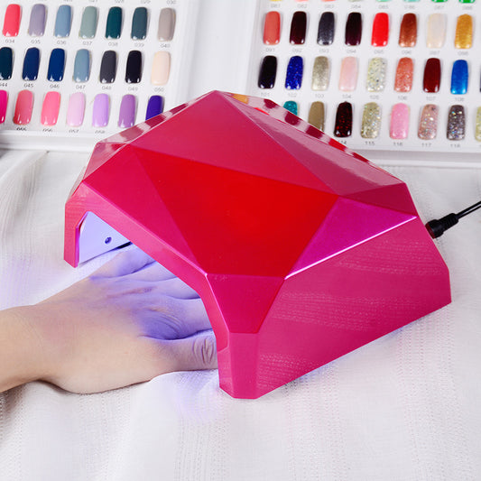 Pink diamond-shaped nail lamp with a hand under it, colorful nail polish colors in the background.